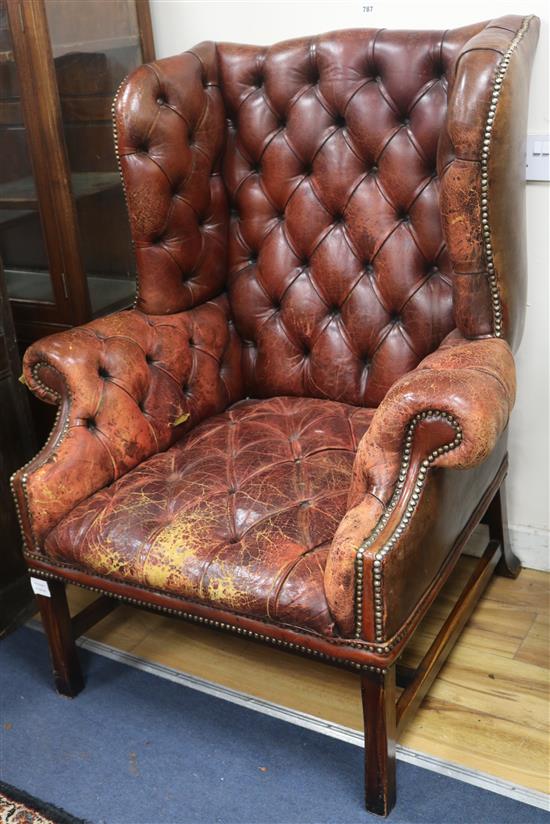 A buttoned leather wing armchair